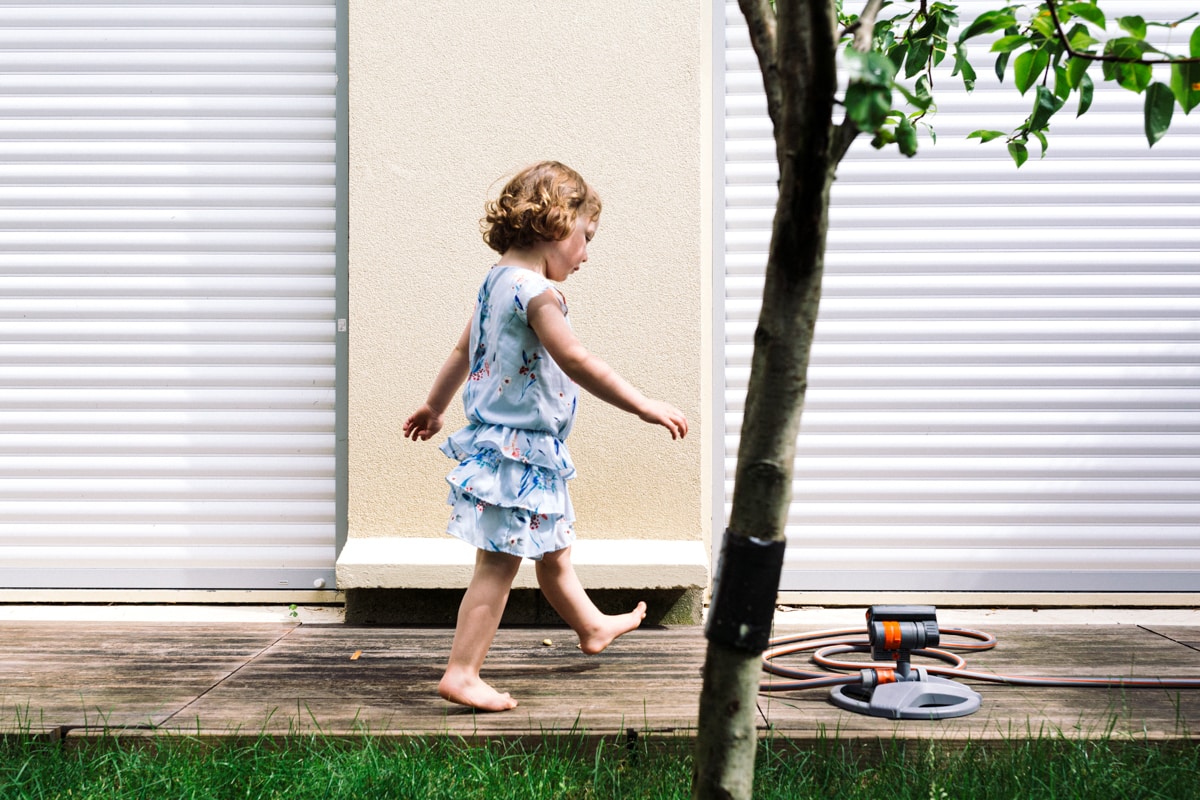 reportage à la maison photo de famille à Rueil Malmaison (92) petite fille qui marche sur la terrasse