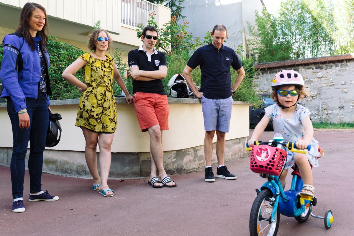 reportage à la maison photo de famille à Rueil Malmaison (92) petite fille a vélo sous le regard des adultes