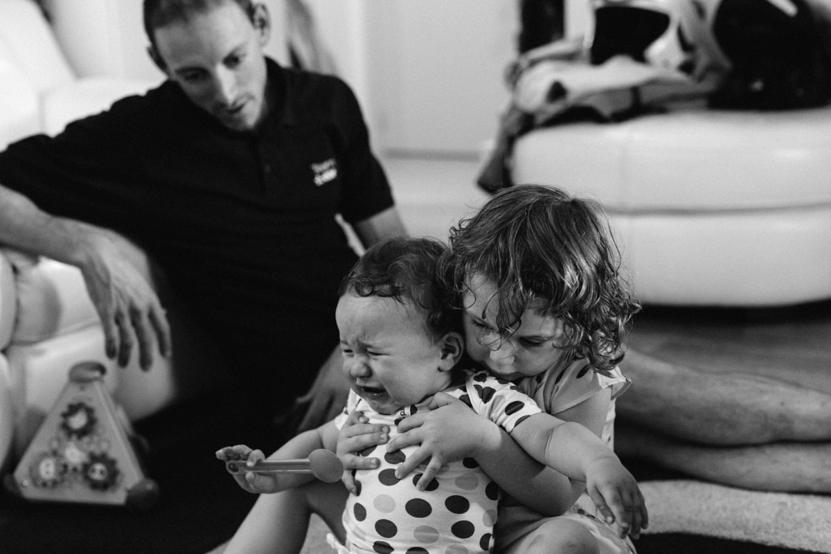 reportage à la maison photo de famille à Rueil Malmaison (92) bébé pleure et grand sœur caline