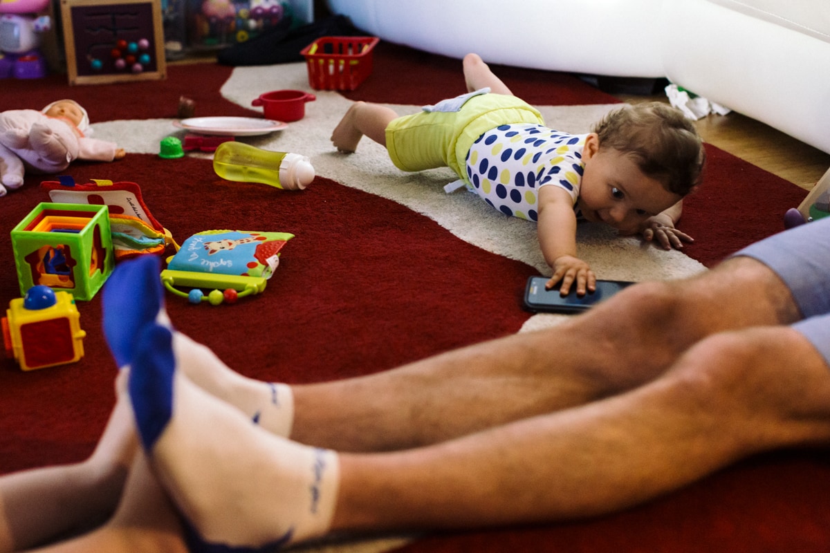 reportage à la maison photo de famille à Rueil Malmaison (92) bébé qui attrape un téléphone portable