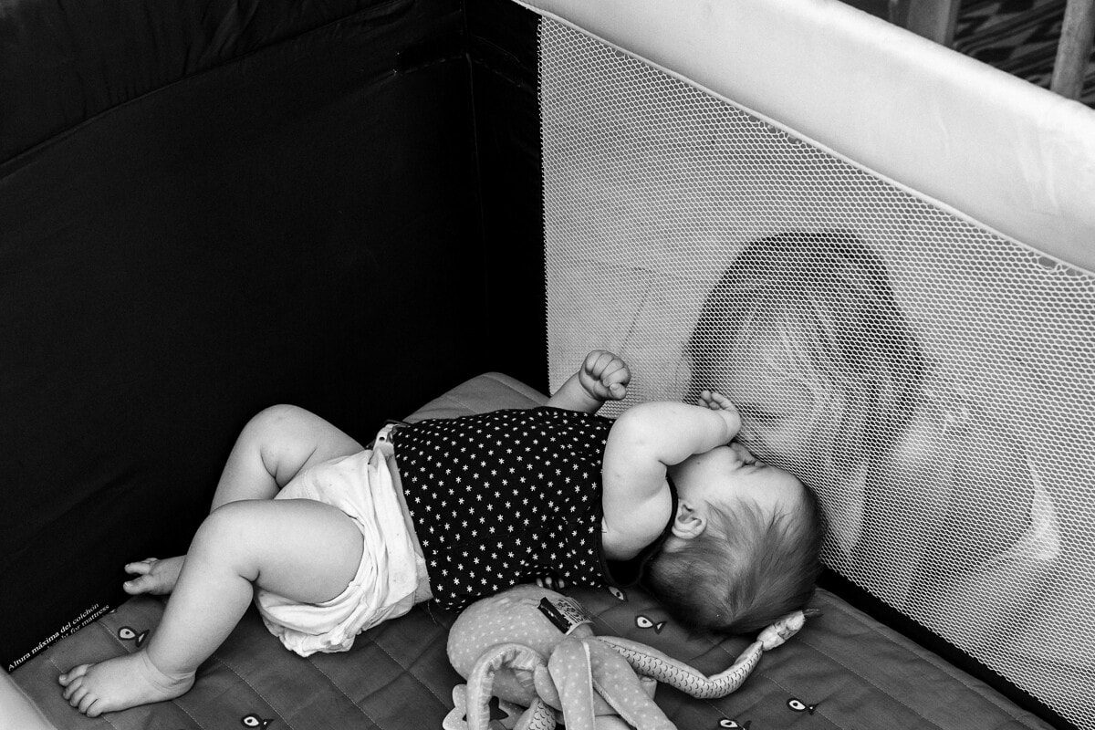 Ernestine-et-sa-famille-wedding and life photographer_-65 ‣ Photographe de famille à l'approche documentaire pour vos évènements ou votre vie quotidienne, à Paris et dans toute la France grande soeur qui fait un bisous à sa petite sœur dans un lit parapluie à travers la maille. Reportage de famille à Lille (59)