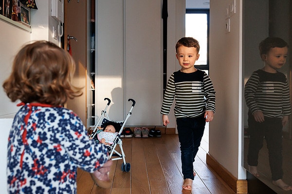 Petit garçon qui marche à coté de la poussette et de sa soeur. Reportage de vie quotidienne à domicile à Issy les Moulineaux.